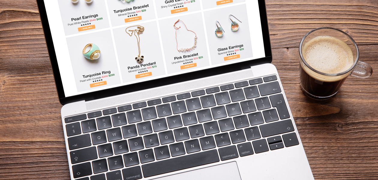 All-in-one: Berufshaftpflicht für etsy Händler Ein Laptop steht auf einem Holztisch. Auf dem Bildschirm sind verschiedene Schmuckstücke zum Kauf zu sehen. Neben dem Laptop steht eine Tasse Kaffee.